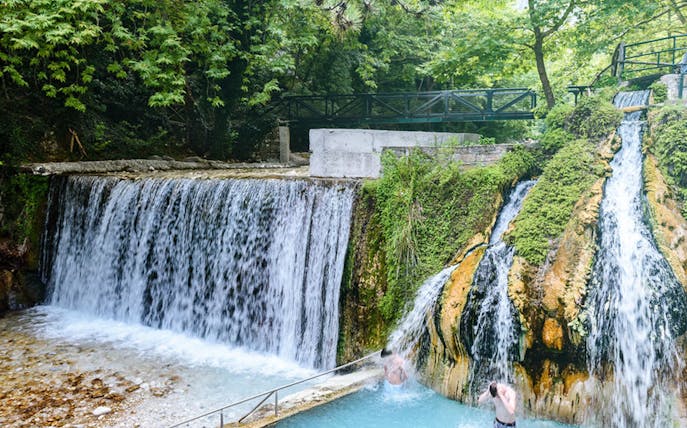 Pozar Thermal Baths waterfall with visitors enjoying the natural hot springs near Edessa, Greece.