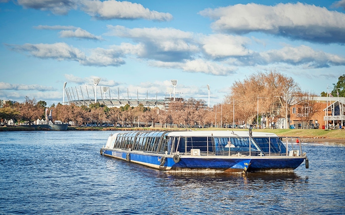 Ferry cruising on Yarra River with Melbourne Cricket Ground in the background.