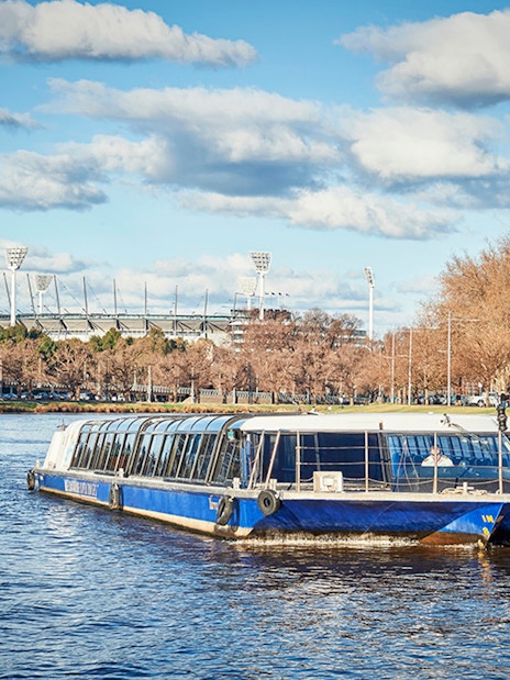 Ferry cruising on Yarra River with Melbourne Cricket Ground in the background.