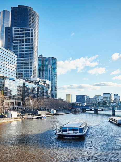 Ferry cruising on Yarra River with Melbourne city skyline in the background.