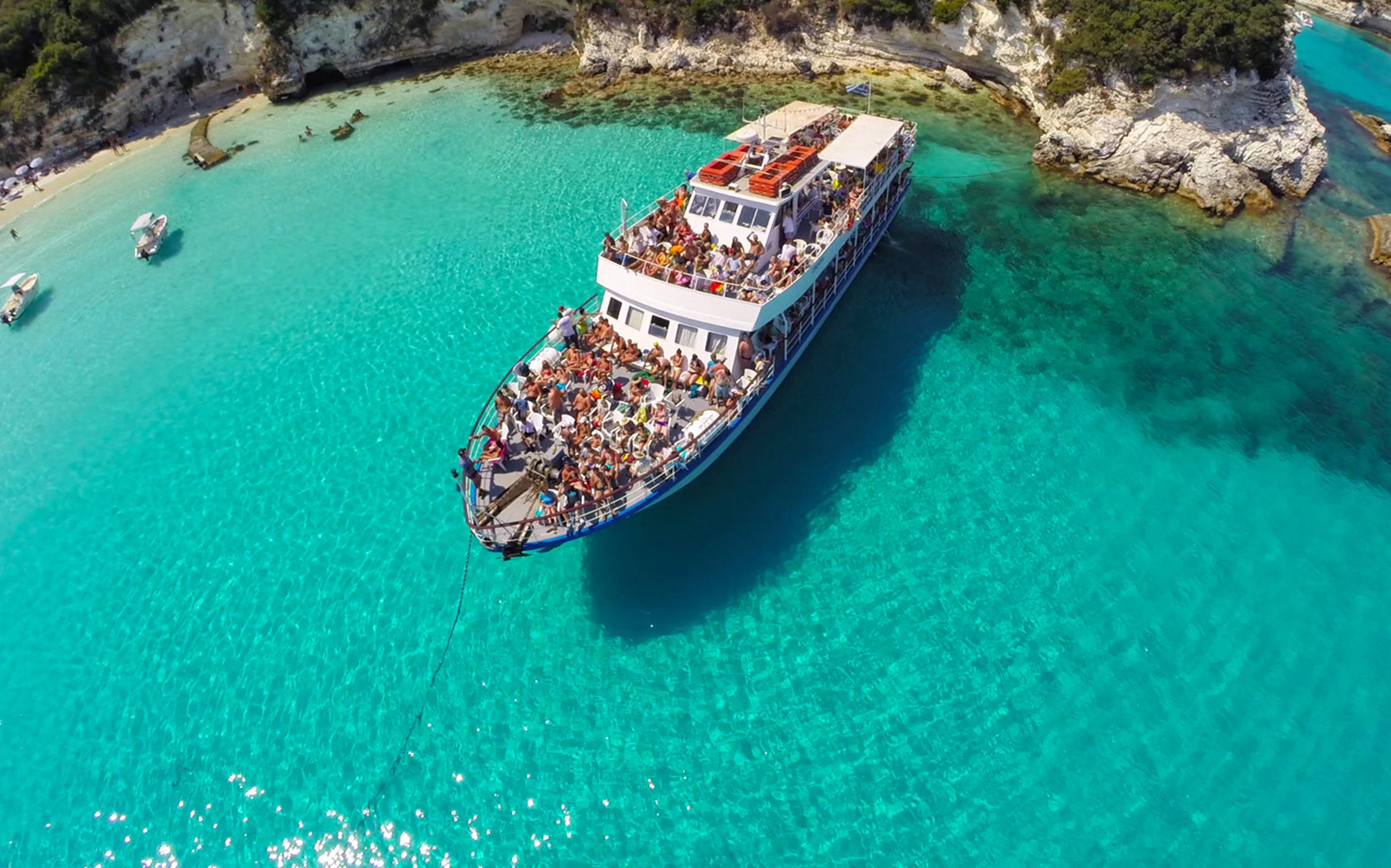 Cruise ship with tourists in turquoise waters near Paxos and Antipaxos.