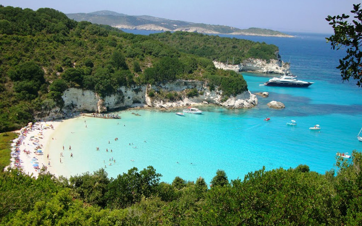 Paxos beach with turquoise waters and boats, part of the Paxos, Antipaxos & Blue Caves Cruise from Corfu.