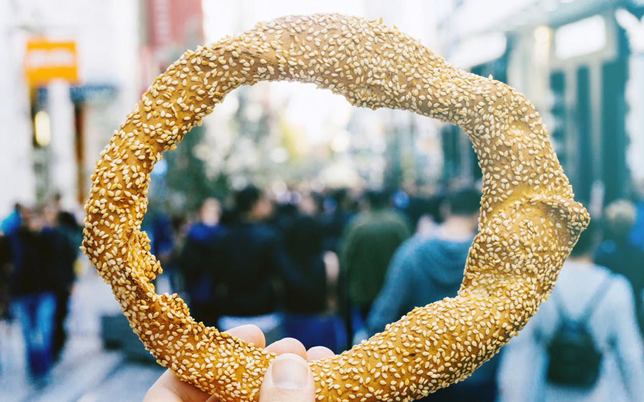 Sesame-covered bread ring held in Thessaloniki market during food tasting tour.