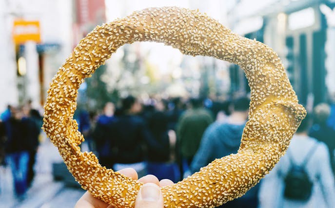 Sesame-covered bread ring held in Thessaloniki market during food tasting tour.