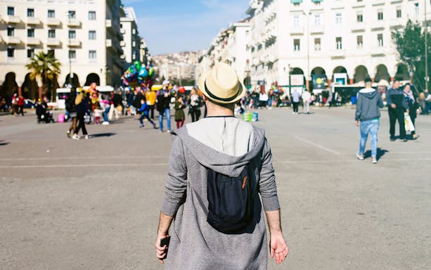 Person walking through a busy square in Thessaloniki, Greece, during a food tasting tour.