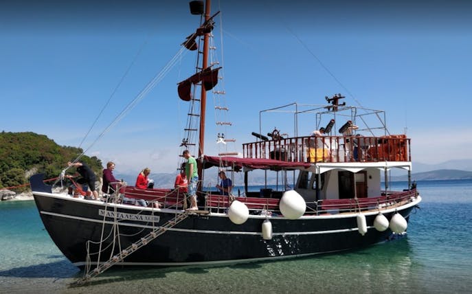 Boat with tourists on a full-day trip in Corfu, Greece, anchored near a scenic coastline.