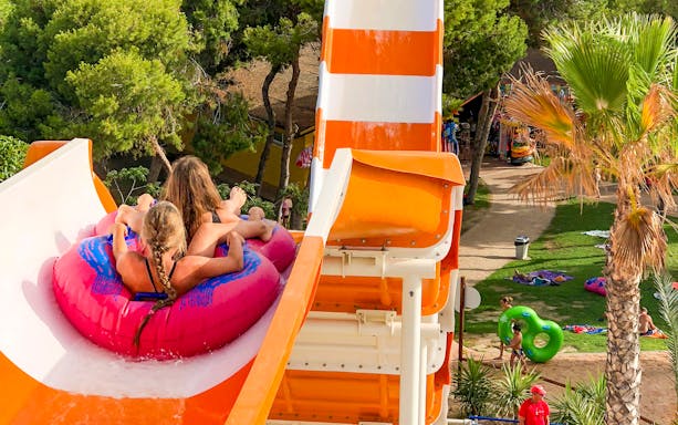 Visitors on a pink raft sliding down a water slide at AquaVera Water Park.