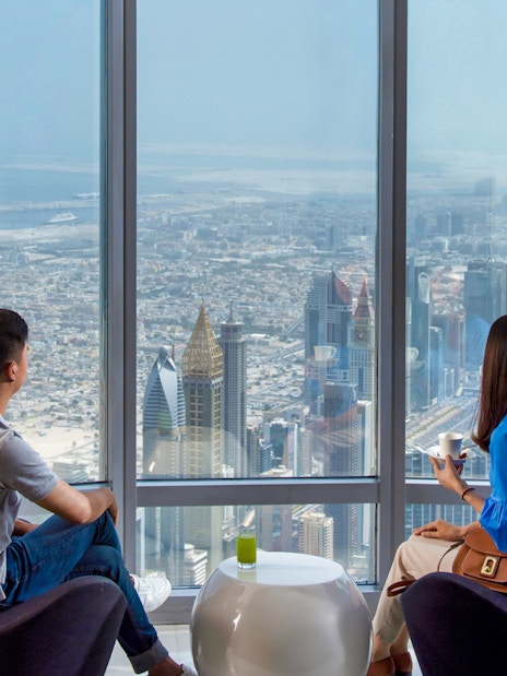 Visitors enjoying the view from Burj Khalifa, overlooking Dubai skyline.