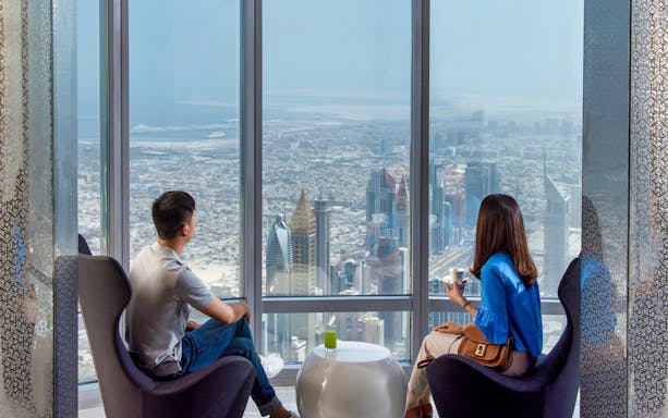 Visitors enjoying the view from Burj Khalifa, overlooking Dubai skyline.