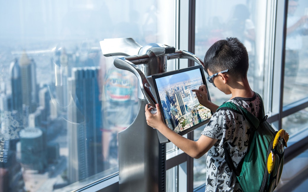 Child using interactive display at Burj Khalifa observation deck, Dubai.