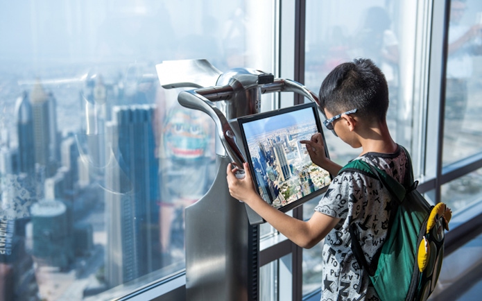 Child using interactive display at Burj Khalifa observation deck, Dubai.