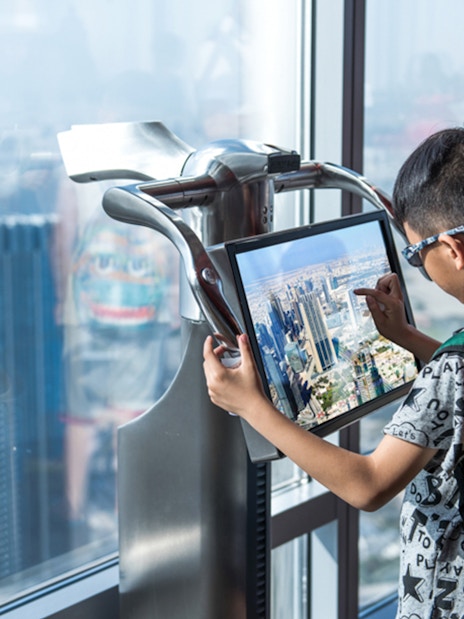 Child using interactive display at Burj Khalifa observation deck, Dubai.