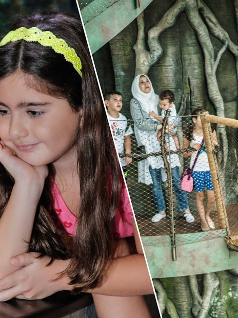 Child observing fish at Dubai Aquarium; family exploring Green Planet's treetop walkway.