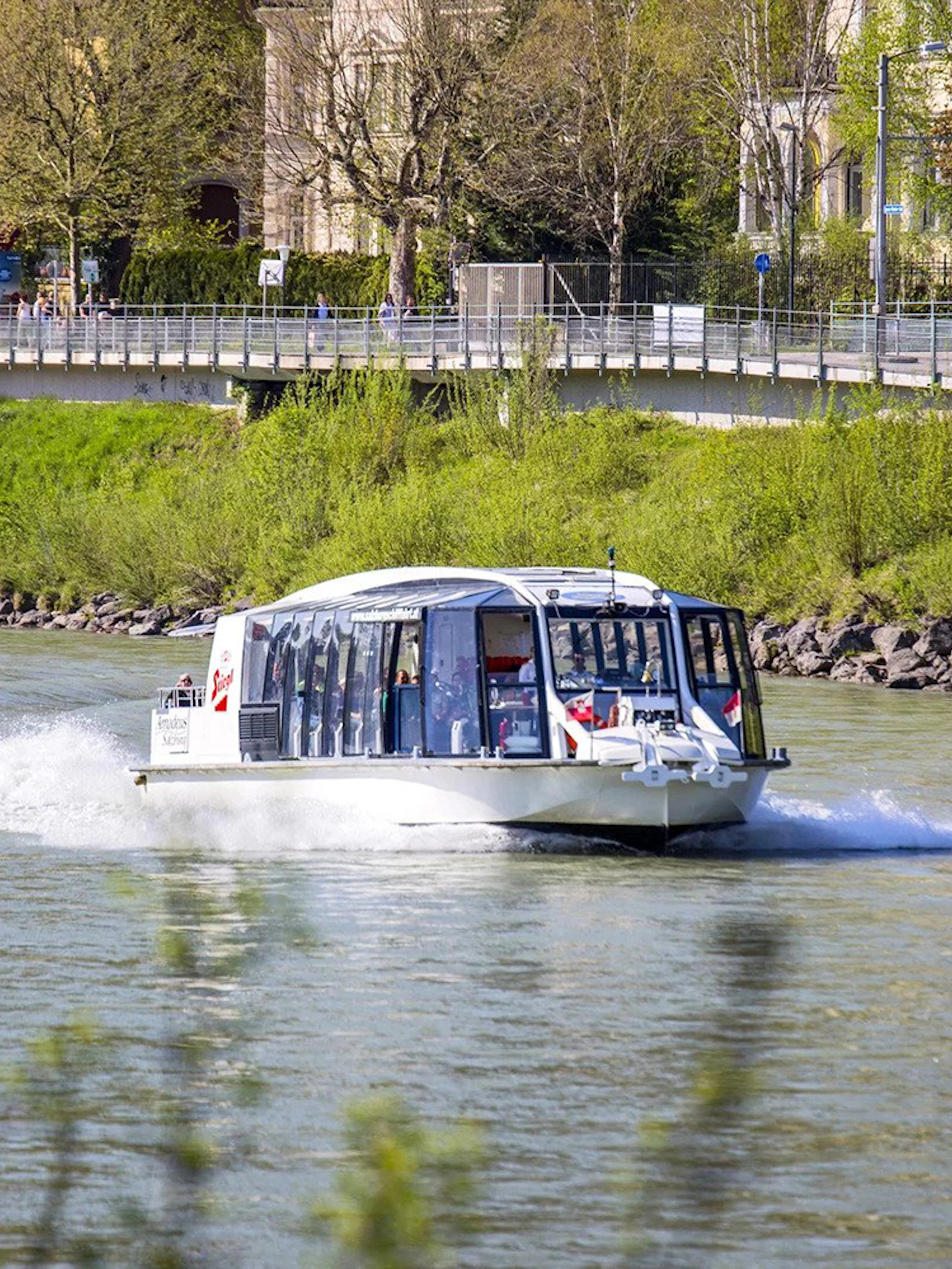 Salzburg river cruise boat on the Salzach River with cityscape in the background.