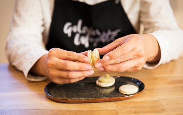 Hands assembling macarons during a workshop at Galeries Lafayette.