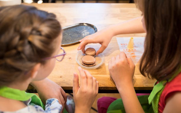 Children making macarons during a family cooking class in France.
