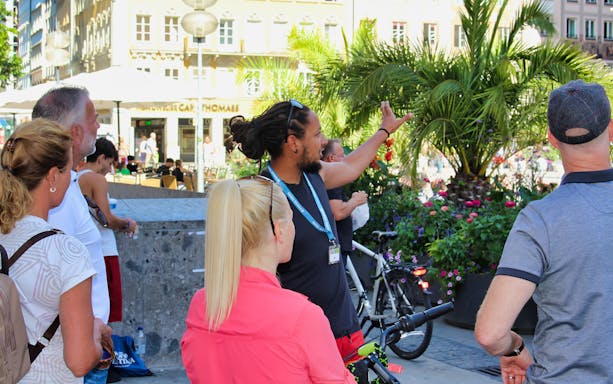 Tour guide leading a group on a Munich bike tour, pointing out city landmarks.
