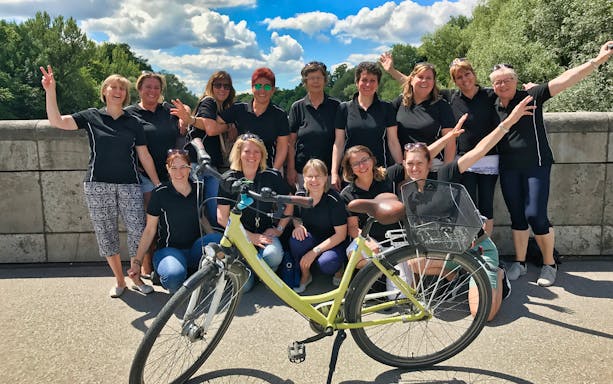 Group of people posing with a bike on a bridge during a Munich bike tour.