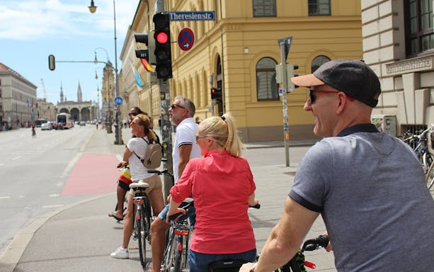 Cyclists on a Munich bike tour pause at a traffic light near Theresienstrasse.