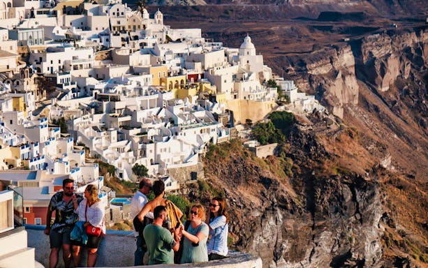 Group of tourists enjoying the view of Santorini's white buildings and cliffs.