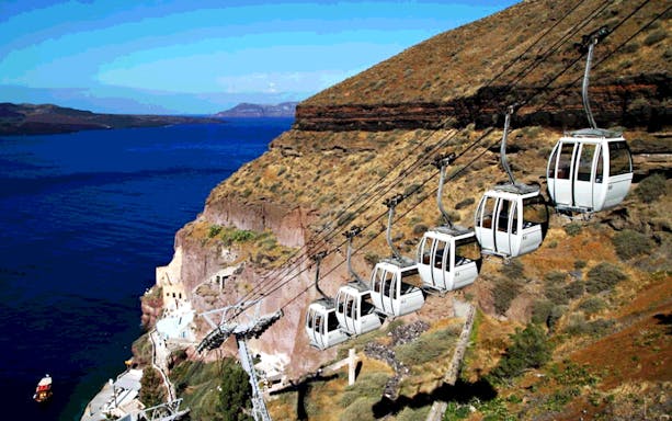 Santorini cable cars ascending cliffside with Aegean Sea view.