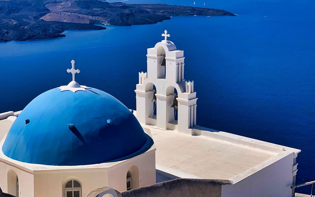 Blue-domed church overlooking the sea in Santorini, Greece.