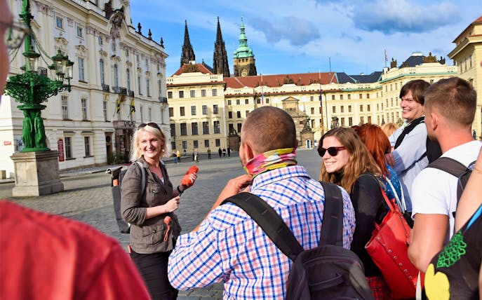 Tour group at Prague Castle courtyard with guide, spires in background.