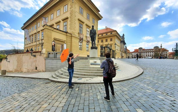 Tourists near statue at Prague Castle, heading to Lobkowicz Palace Café.