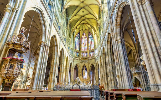 Interior of St. Vitus Cathedral, Prague Castle, with stained glass windows and ornate pulpit.