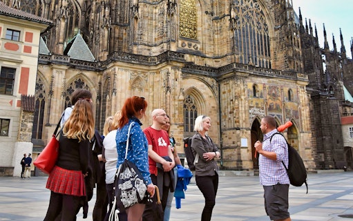 Tour group outside Prague Castle, discussing architecture.