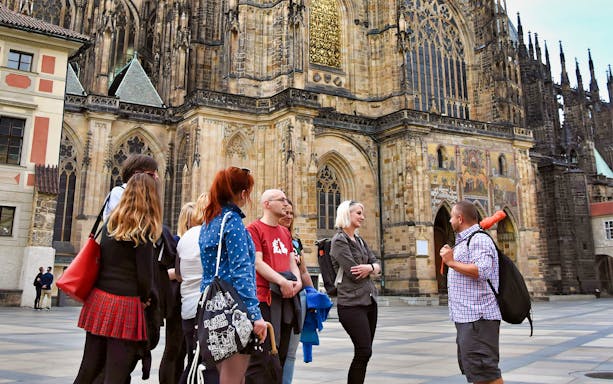 Tour group outside Prague Castle, discussing architecture.