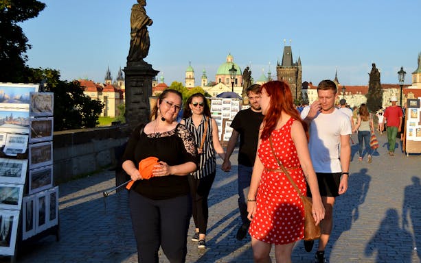 Tourists walking on Charles Bridge in Prague during an evening tour.
