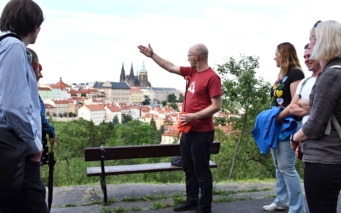 Tour guide leading an evening walk with a view of Prague Castle in the background.