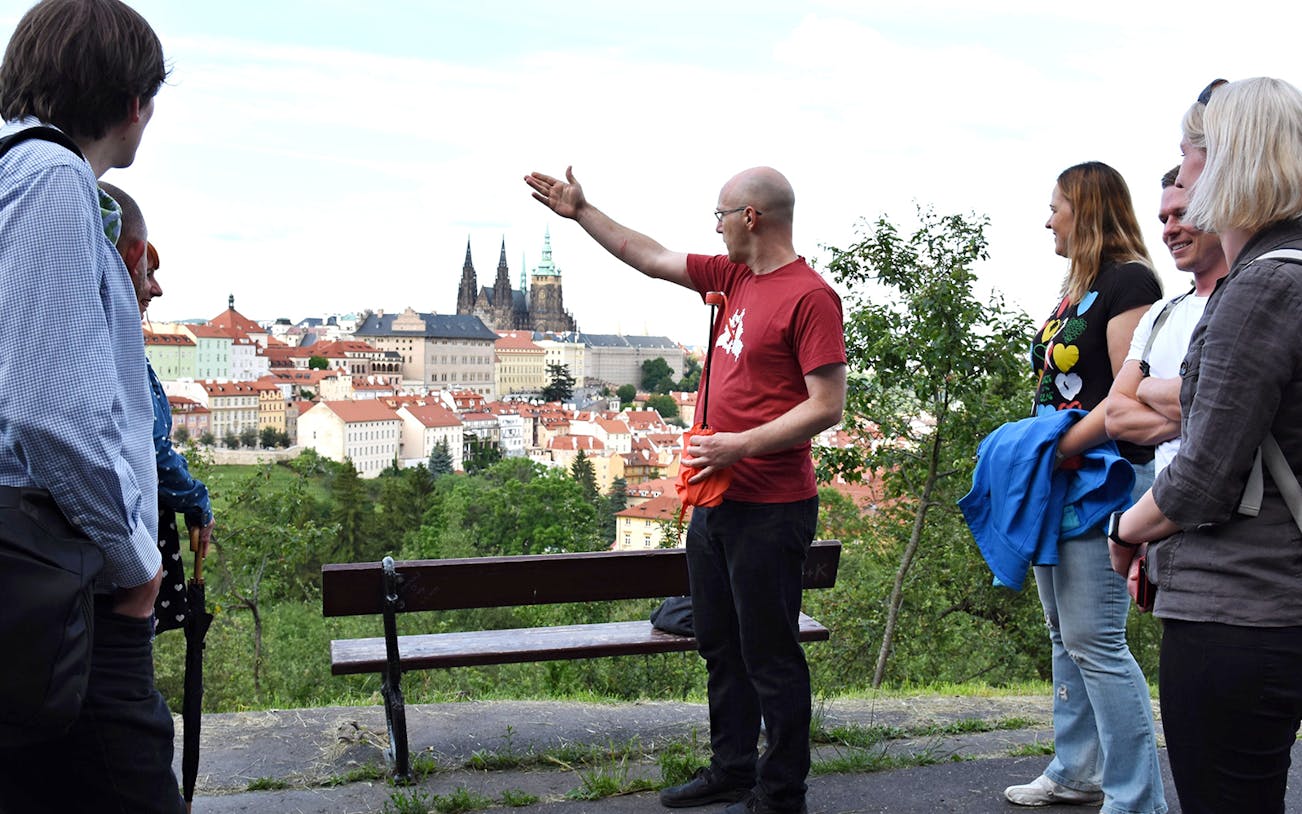 Tour guide leading an evening walk with a view of Prague Castle in the background.