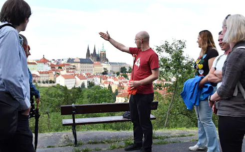 Tour guide leading an evening walk with a view of Prague Castle in the background.