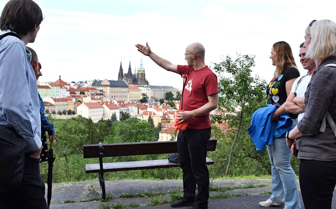 Tour guide leading an evening walk with a view of Prague Castle in the background.