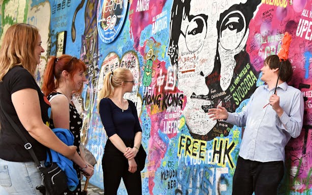 Group of tourists at the John Lennon Wall in Prague during an evening walk.
