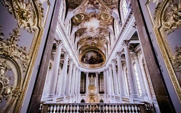 Interior of the Palace of Versailles with ornate ceiling and columns, France.