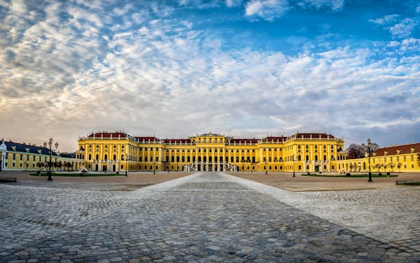 Grand facade of Schönbrunn Palace, Vienna, under a cloudy sky.