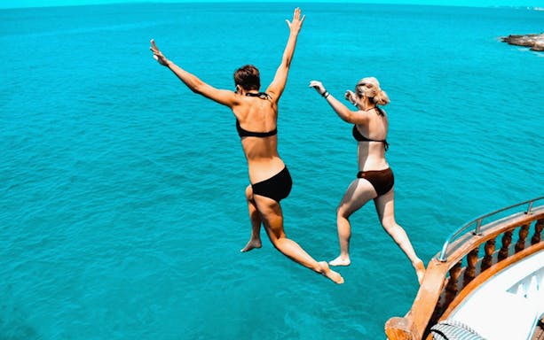 Two people jumping off a boat into the sea during a day cruise from Athens to Agistri, Moni, and Aegina.