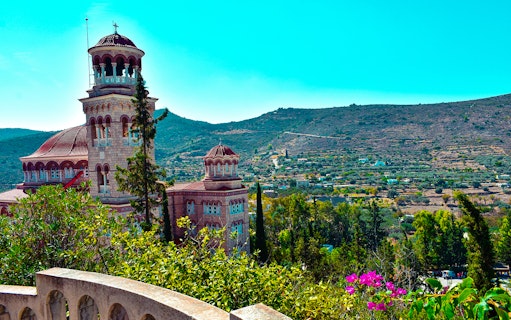 Church with domes and arches on Athens Riviera hillside during night cruise.