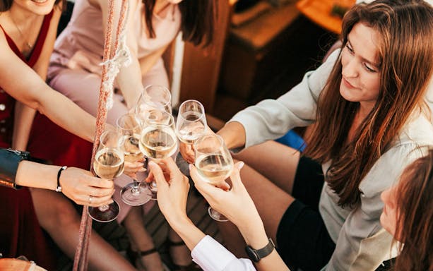 Guests toasting with wine glasses on a night party boat in Athens Riviera.