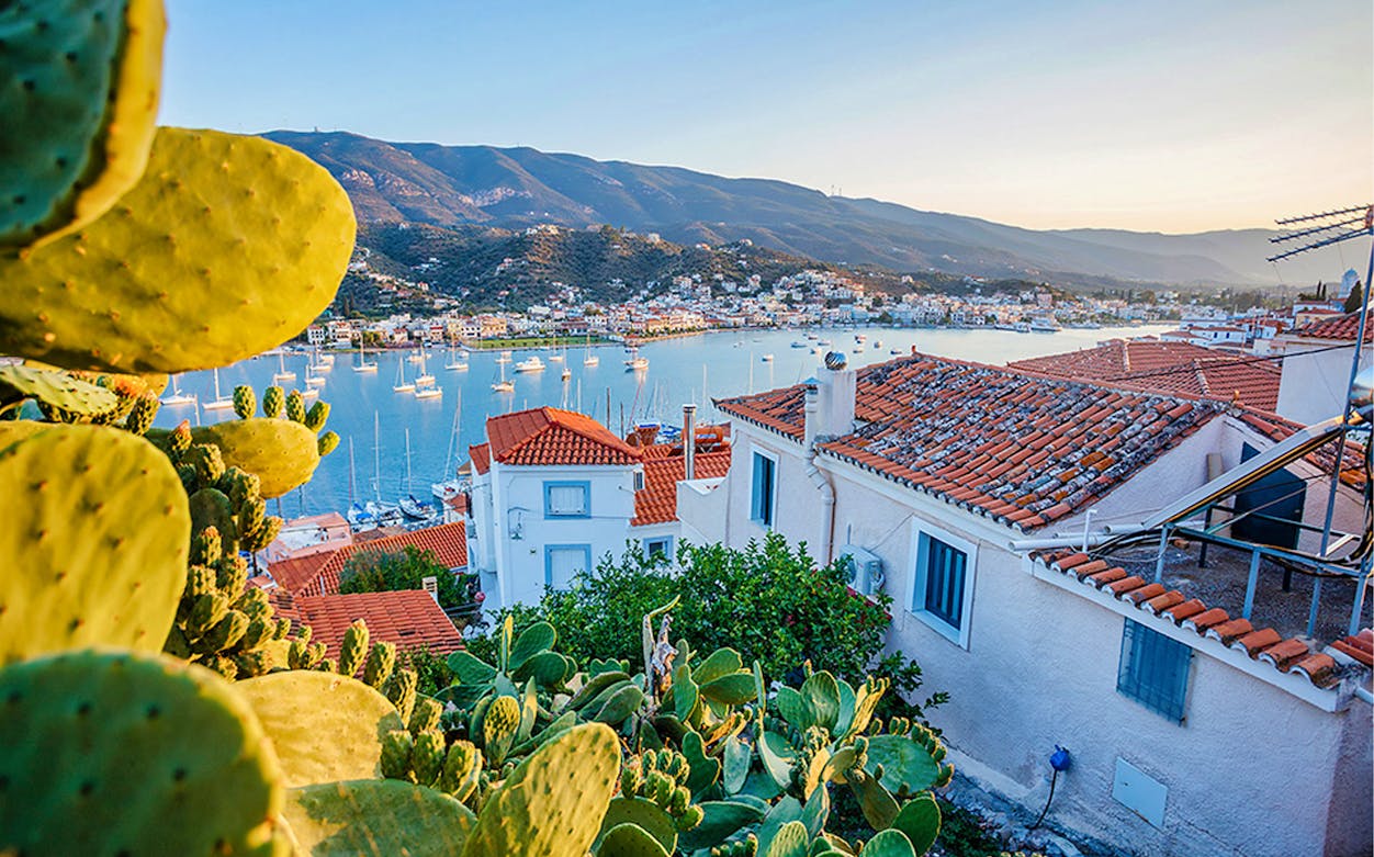 Hydra Island view with red-roofed houses and boats in the harbor, Greece.