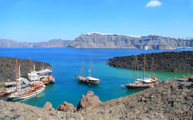 Boats anchored near volcanic rocks on Santorini Volcano Boat Tour.