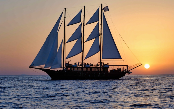 Sailing ship at sunset during Santorini Volcanic Islands cruise.