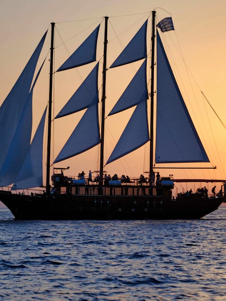 Sailing ship at sunset during Santorini Volcanic Islands cruise.