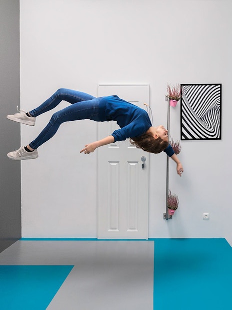 Visitor experiencing gravity-defying illusion at the Museum of Illusions, Vienna.