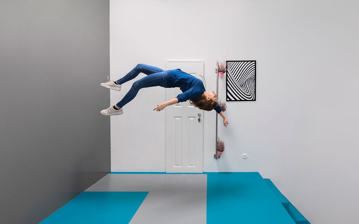 Visitor experiencing gravity-defying illusion at the Museum of Illusions, Vienna.
