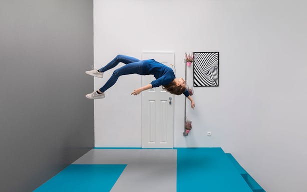 Visitor experiencing gravity-defying illusion at the Museum of Illusions, Vienna.