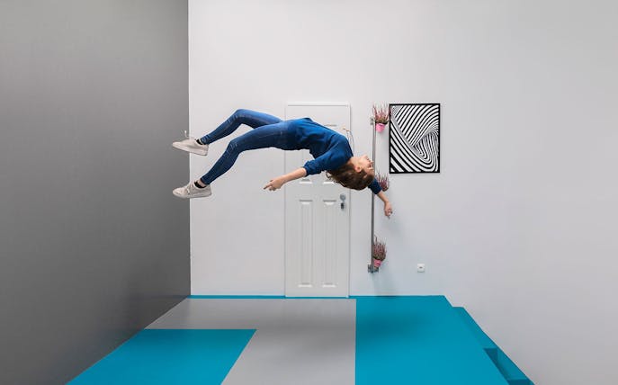 Visitor experiencing gravity-defying illusion at the Museum of Illusions, Vienna.